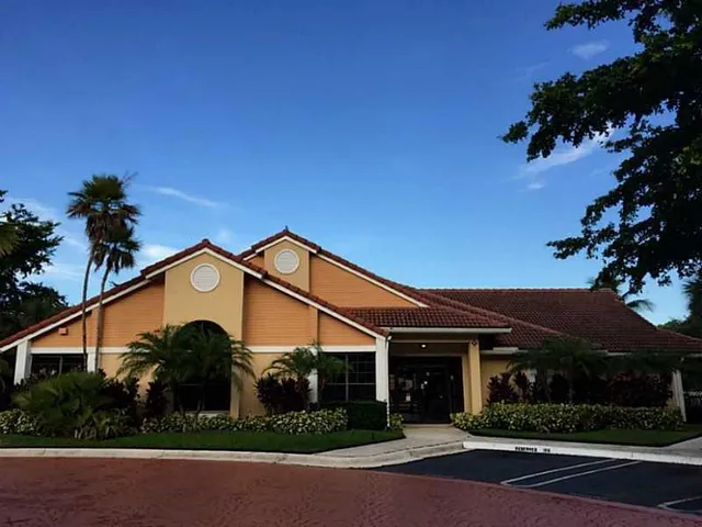 a view of a white house next to a yard with potted plants