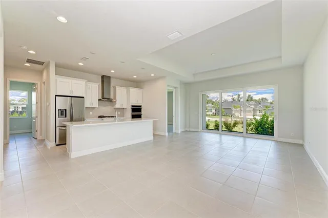a large white kitchen with a large window and a refrigerator