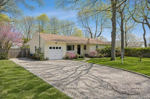a view of a white house next to a yard with big trees