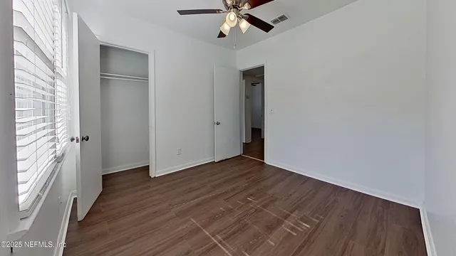 a view of an empty room with wooden floor and a window