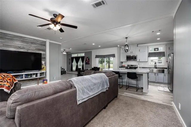 a living room with furniture kitchen area and a chandelier