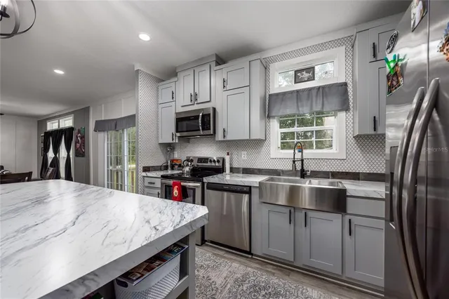 a kitchen with granite countertop a sink a counter space appliances and cabinets