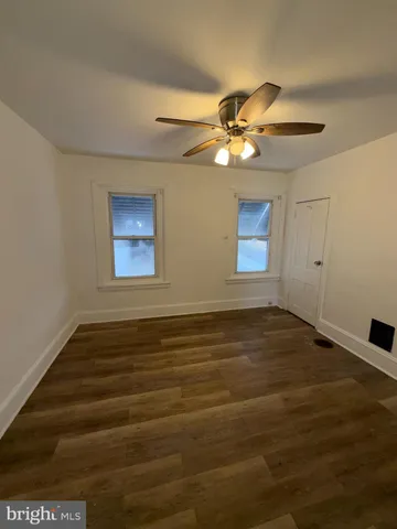 a view of an empty room with chandelier fan and wooden floor
