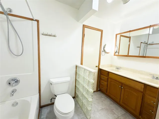 a bathroom with a toilet sink vanity tub and mirror