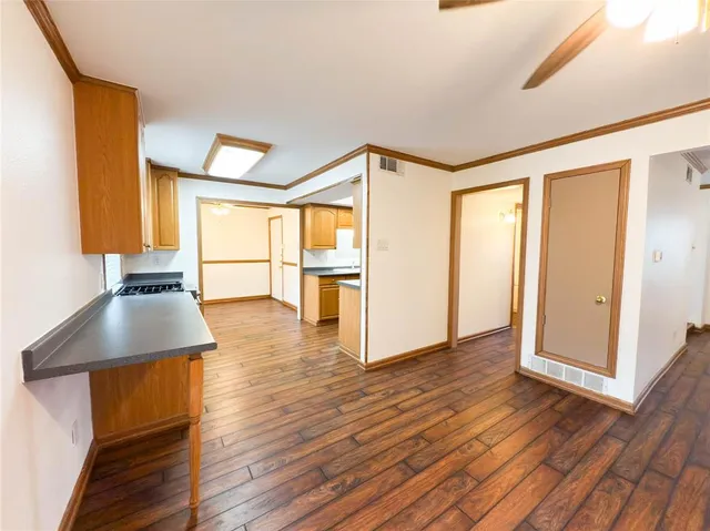 a view of a livingroom with wooden floor and a kitchen
