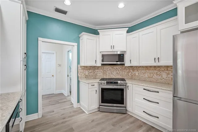 a kitchen with white cabinets and stainless steel appliances