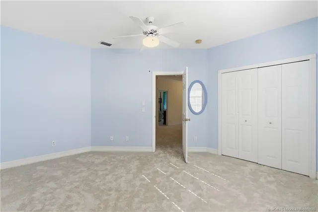 a view of an empty room with window and a ceiling fan