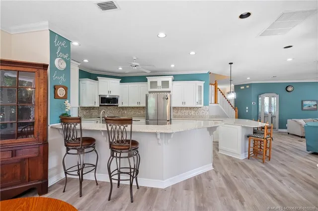 a kitchen with stainless steel appliances kitchen island granite countertop a table chairs and a refrigerator