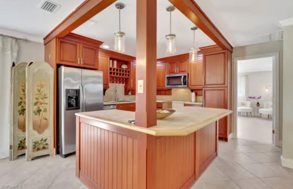 116 Capri Boulevard Naples, FL 34113 - Photo 3 of 29 Kitchen featuring visible vents, light tile patterned flooring, stainless steel appliances, light countertops, and pendant lighting