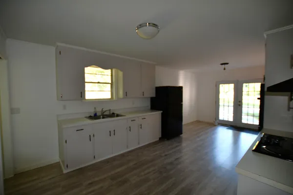 a kitchen with granite countertop a stove a sink a refrigerator and wooden floor