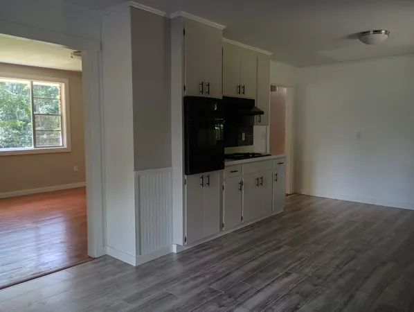 an empty room with wooden floor and cabinet