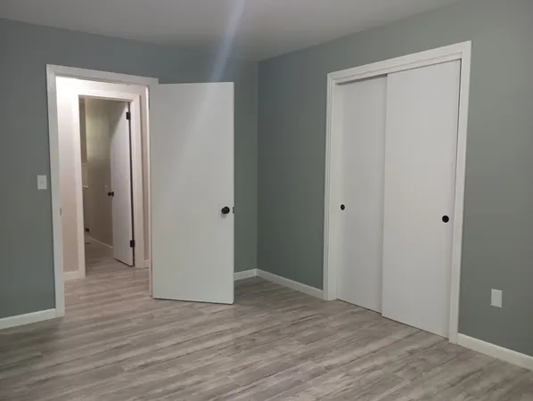 a view of an empty room with wooden floor and closet