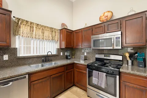 a kitchen with granite countertop a sink a stove a microwave and cabinets