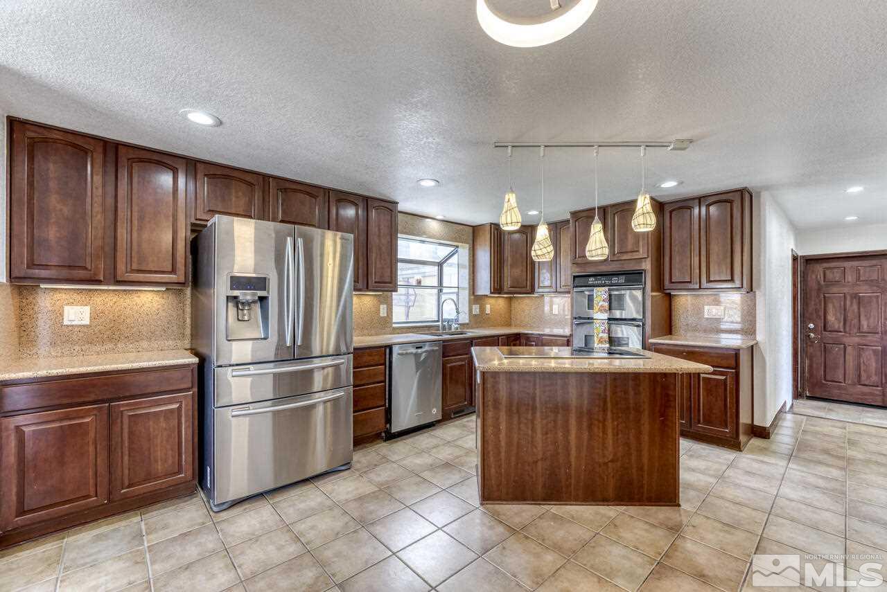 650 Desert Shadows Lane Fernley, NV 89408 - Photo 3 of 39 a kitchen with kitchen island granite countertop wooden cabinets and stainless steel appliances