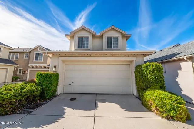 a view of a white house with large windows and a yard with plants