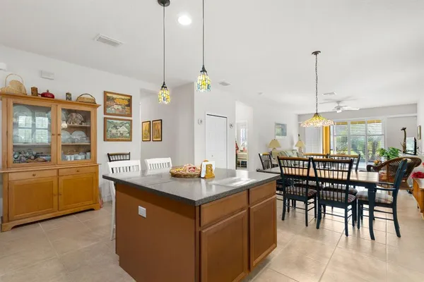 a dining hall with stainless steel appliances granite countertop a stove a sink a dining table and chairs
