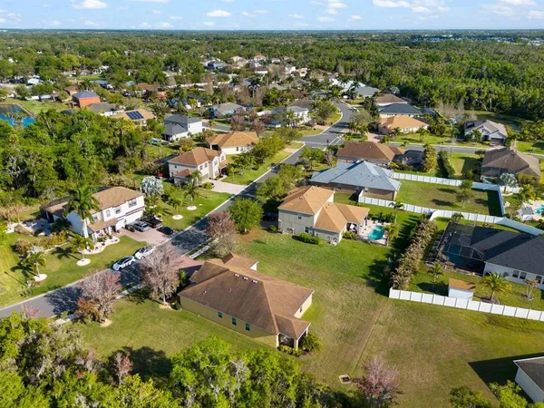 an aerial view of residential houses with outdoor space and trees