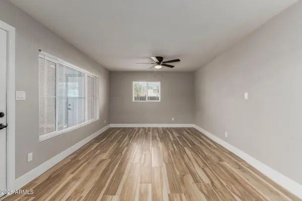 a view of an empty room with wooden floor and a window