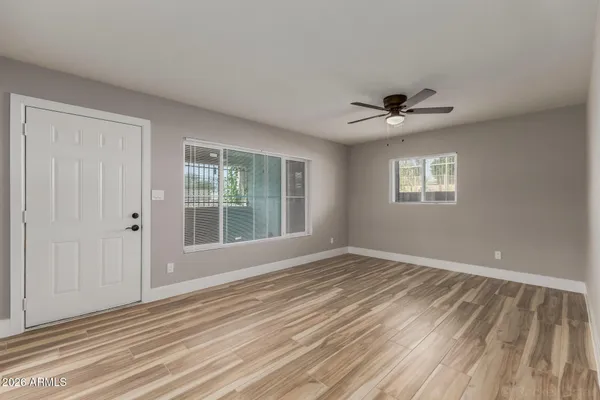 a view of an empty room with a window and a kitchen