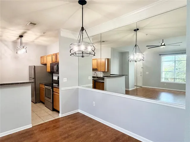 an empty room with wooden floor chandelier fan and windows