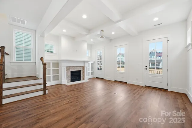 an empty room with wooden floor a fireplace and windows