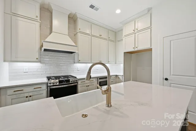 a kitchen with stainless steel appliances granite countertop a sink a stove and a refrigerator