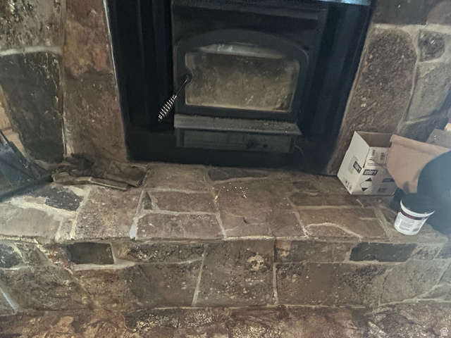 19075 West Honesty Cove Duchesne, UT 84021 - Photo 24 of 44 Stone hearth and fireplace with dark metal insert, complemented by wood-finish flooring and a textured area rug