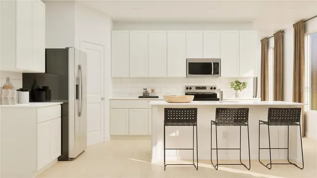 a kitchen with stainless steel appliances kitchen island granite countertop a refrigerator a stove a sink and white cabinets with wooden floor