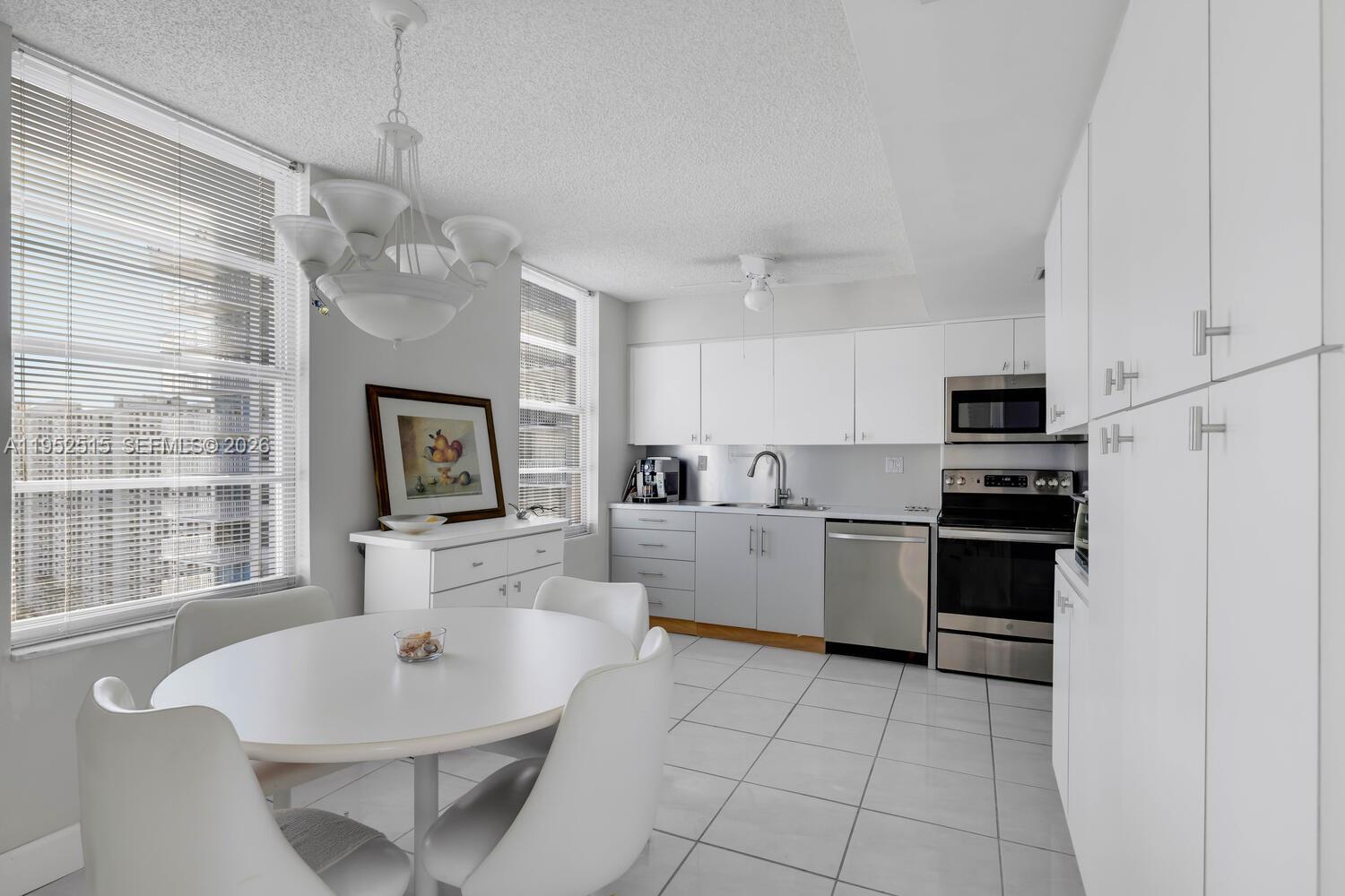 231 174th Street, Unit 2018 Sunny Isles Beach, FL 33160 - Photo 9 of 25 a large white kitchen with a stove a sink dishwasher and a refrigerator with wooden floor