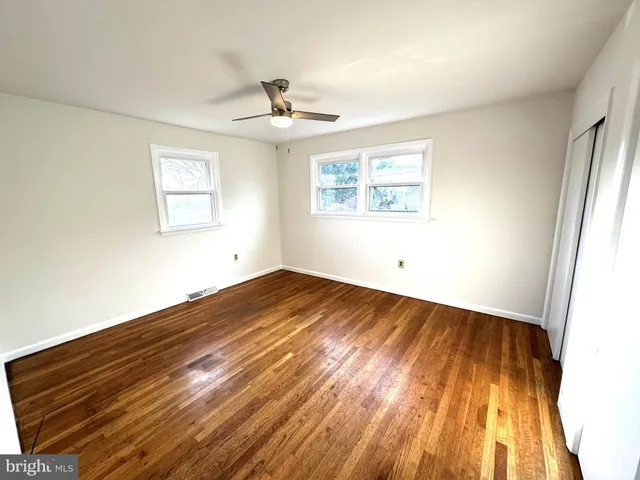 a view of empty room with wooden floor and fan