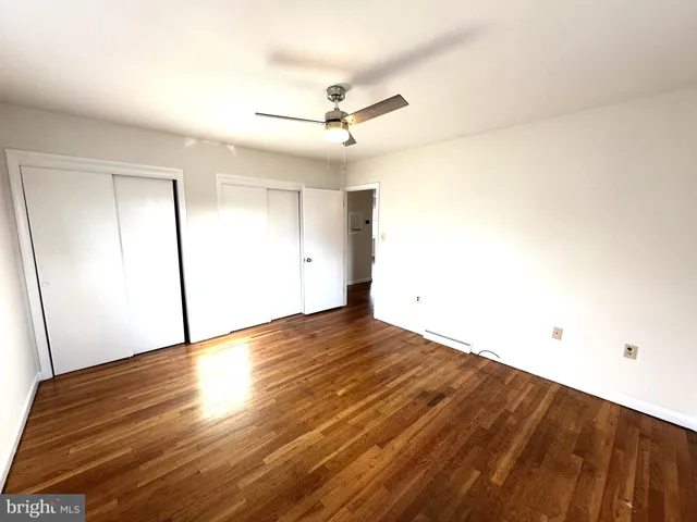 an empty room with wooden floor and fan