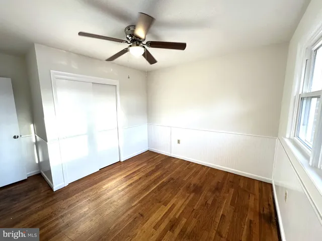an empty room with wooden floor fan and windows