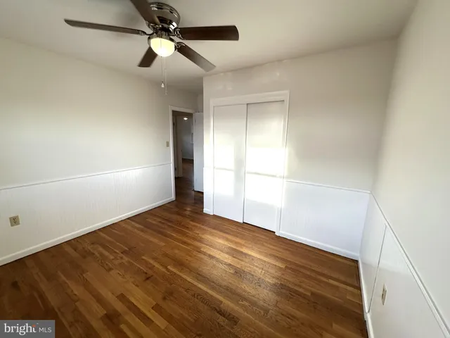 a view of empty room with wooden floor and fan