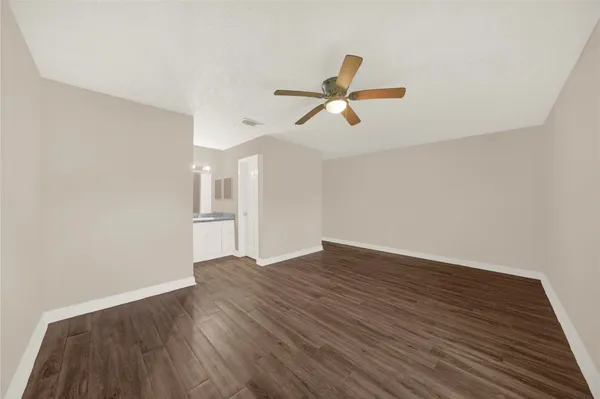 a view of empty room with wooden floor and ceiling fan