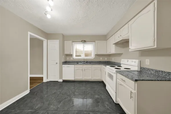 a kitchen with granite countertop white cabinets and white appliances