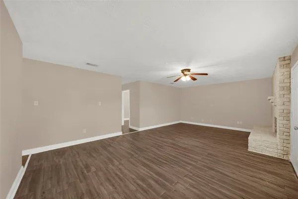 an empty room with wooden floor ceiling fan and window