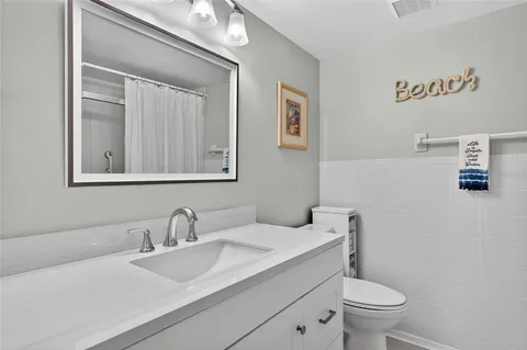 a bathroom with a granite countertop toilet sink and mirror