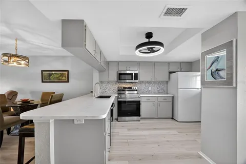 a kitchen with stainless steel appliances granite countertop a sink a stove a refrigerator and white cabinets