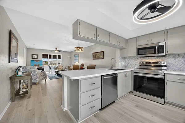 a kitchen with stainless steel appliances granite countertop a stove top oven a sink dishwasher and white cabinets with wooden floor