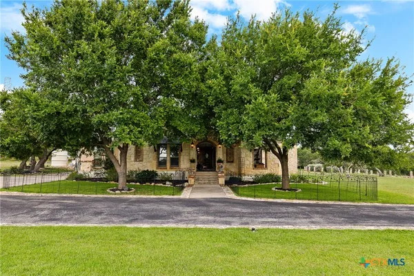 a front view of a house with garden and trees