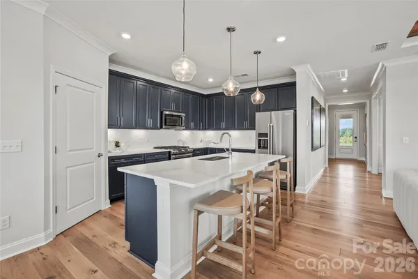 a kitchen with stainless steel appliances kitchen island granite countertop a refrigerator a stove a sink dishwasher and a dining table with wooden floor