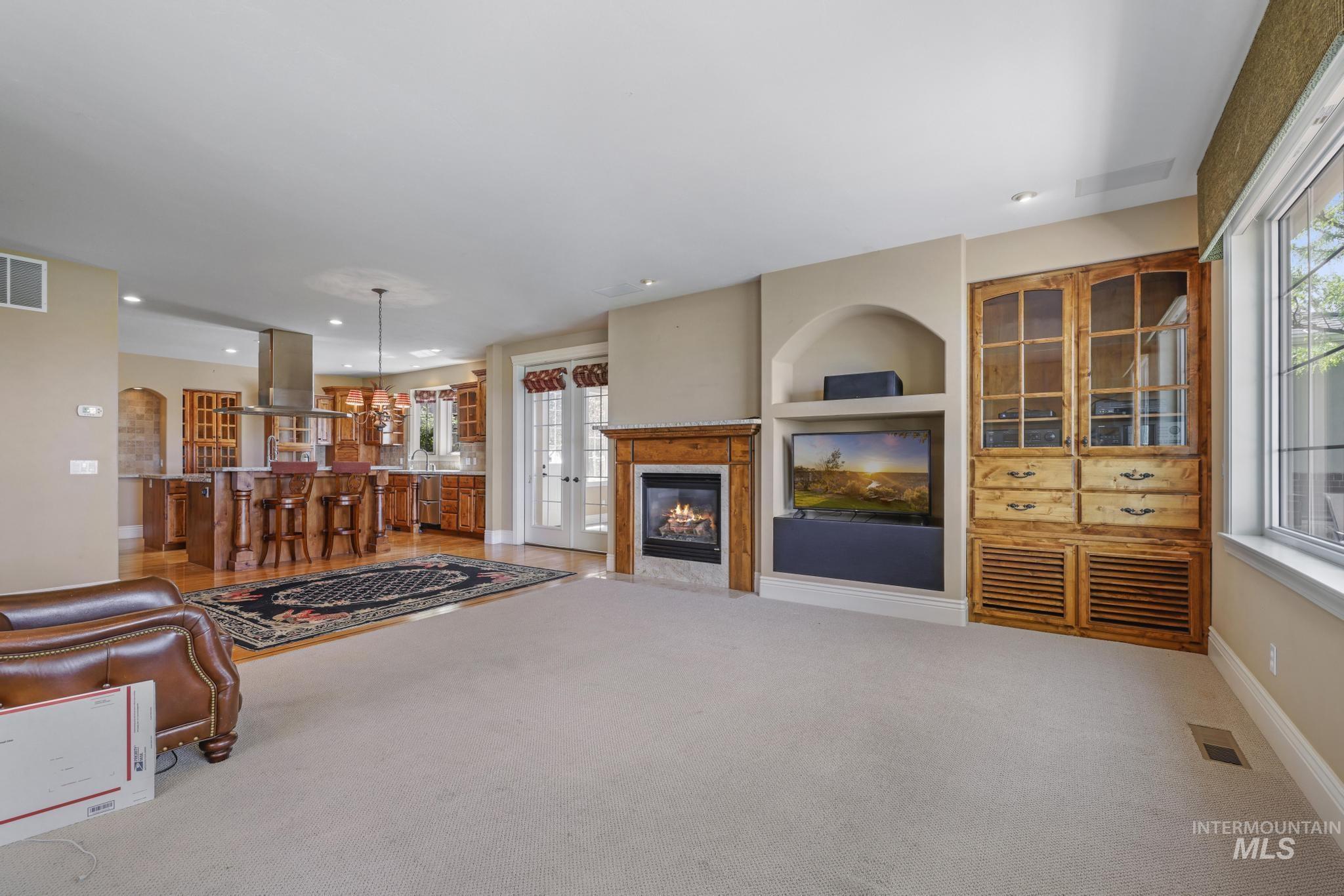 1526 Highway 26 Gooding, ID 83330 - Photo 13 of 48 Living area with light carpet, a premium fireplace, built in shelves, a chandelier, and arched walkways