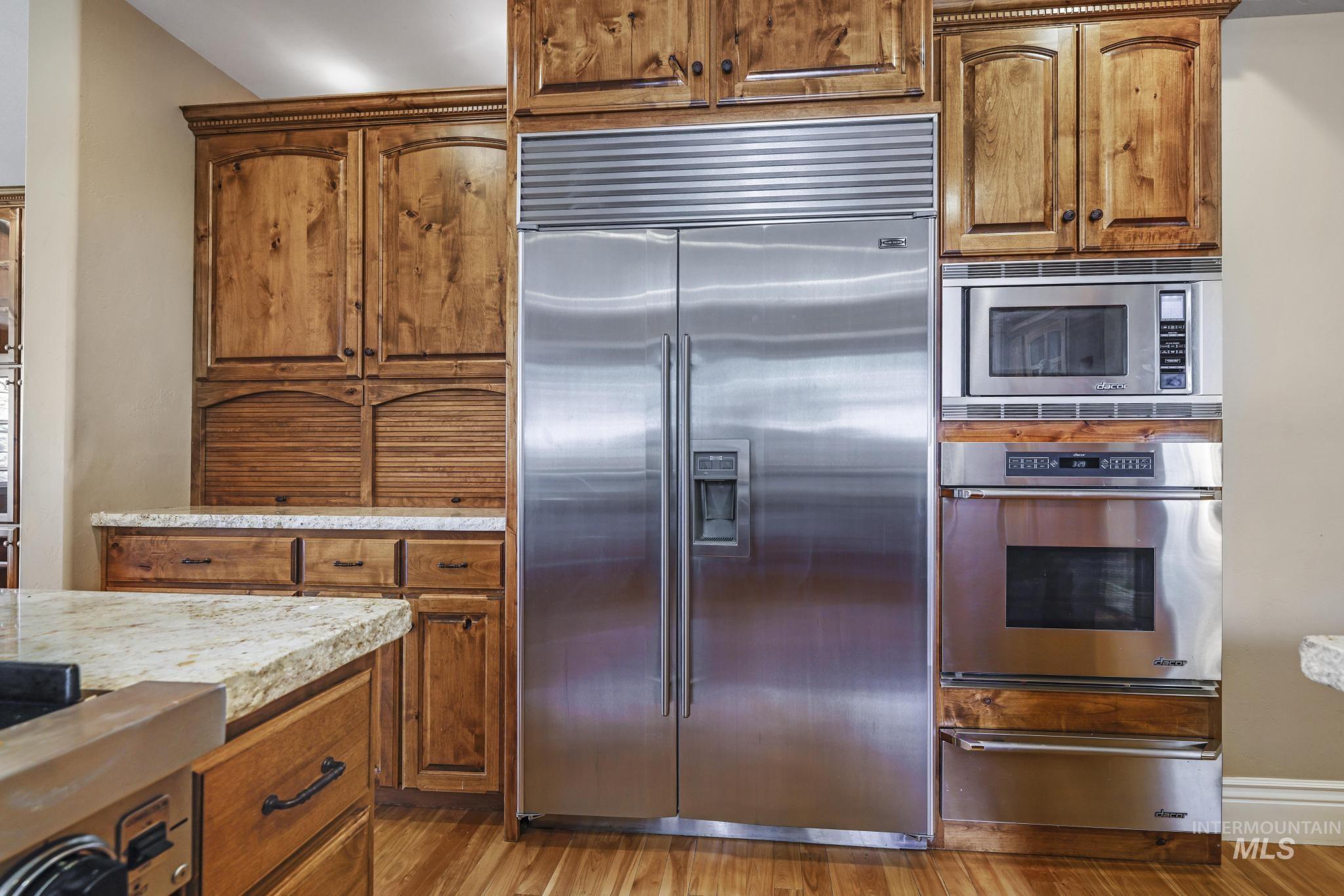 1526 Highway 26 Gooding, ID 83330 - Photo 16 of 48 Kitchen with brown cabinets, built in appliances, a warming drawer, light wood-type flooring, and light stone countertops