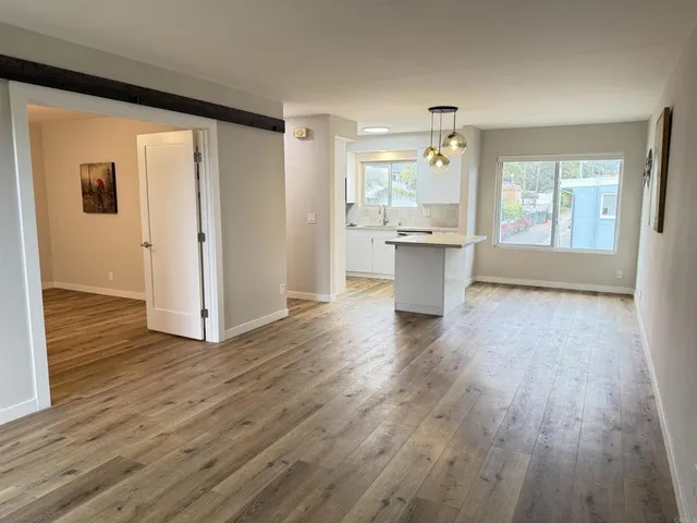 a large kitchen with a wooden floor and a window