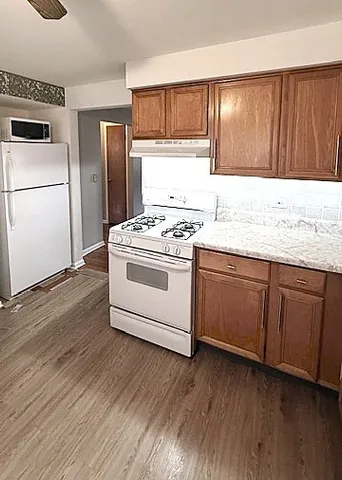 a kitchen with a sink a refrigerator and wooden floor