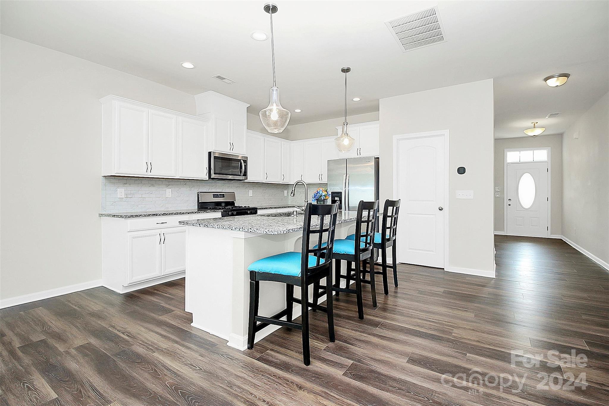 1769 Bailey Ridge Drive York, SC 29745 - Photo 17 of 47 a kitchen with stainless steel appliances granite countertop a stove a refrigerator a microwave a dining table and chairs with wooden floor