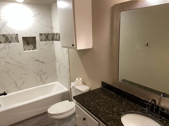 a bathroom with a granite countertop sink toilet and shower