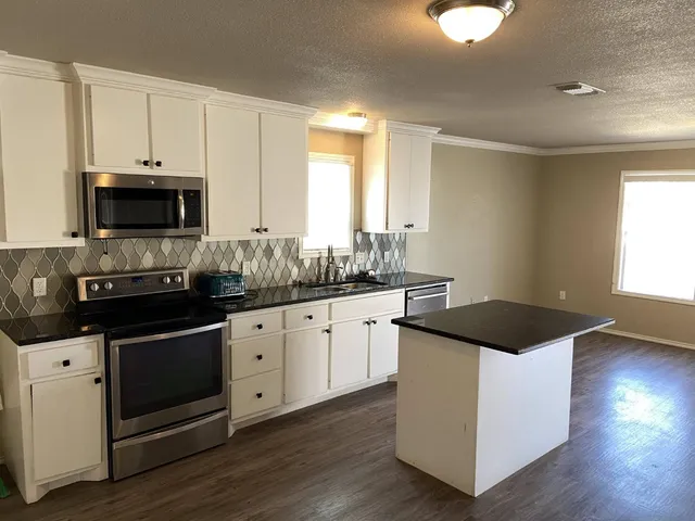 a kitchen with granite countertop a sink and a stove top oven