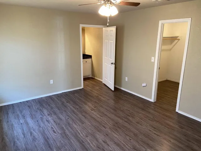 an empty room with wooden floor and a ceiling fan