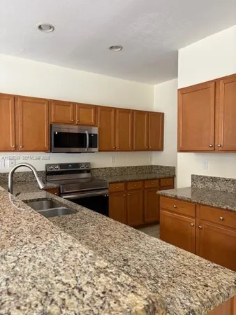 a kitchen with stainless steel appliances granite countertop a sink refrigerator and cabinets
